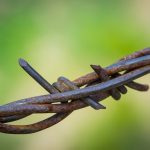 Wrapped metal strands of barbed wire fence.wired tired stress